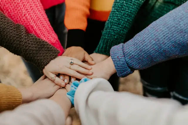 Group stacking hands together in colourful sweaters