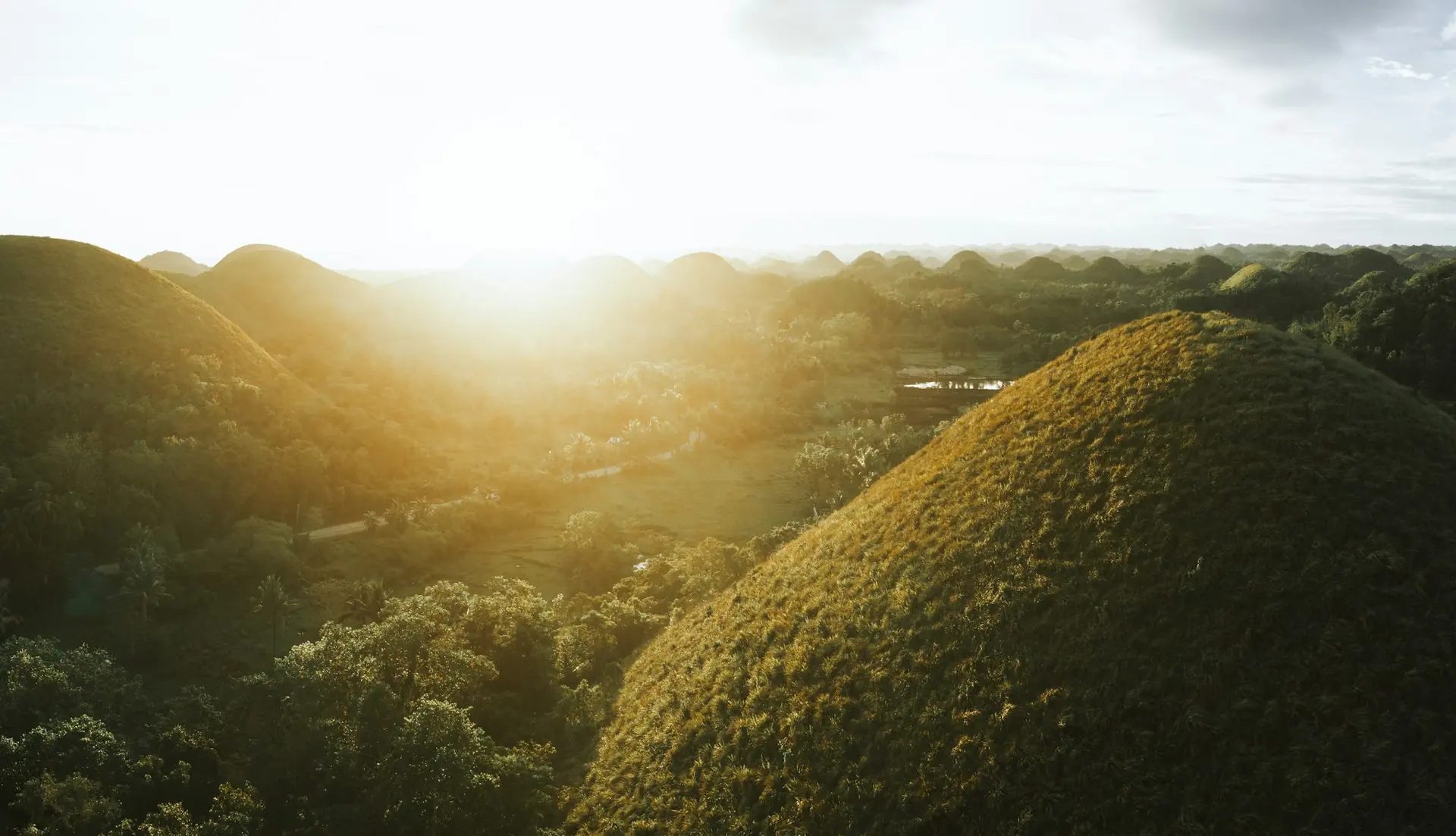 Sunlight breaking through clouds over green rolling hills