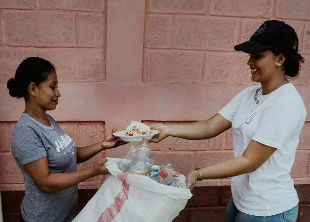 Volunteer handing a plate of food to a woman at an outreach