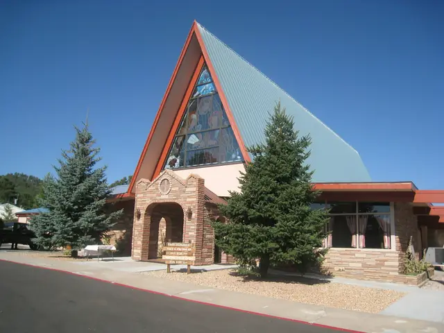 Modern A-frame church building with a steep roof among green trees